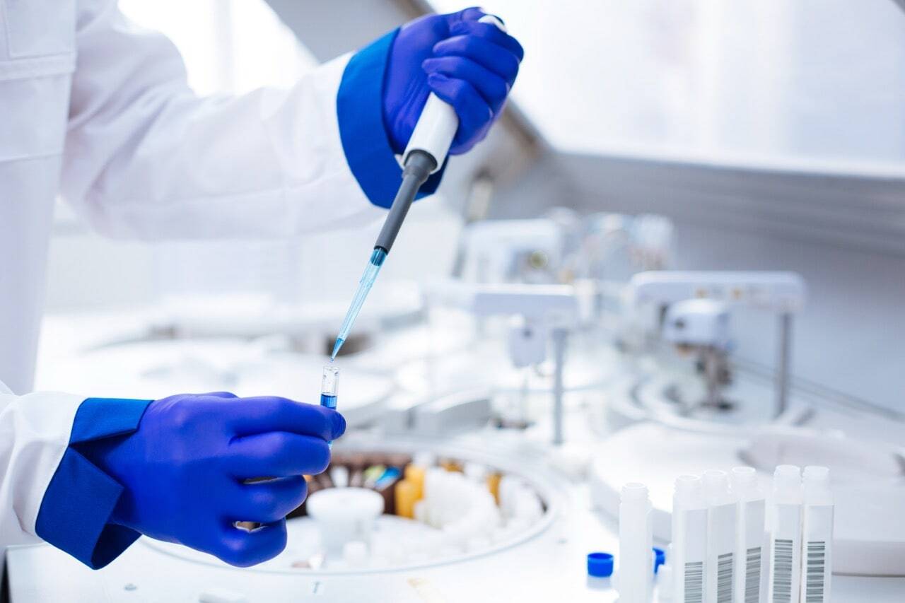 hands-in-blue-gloves-holding-pipette